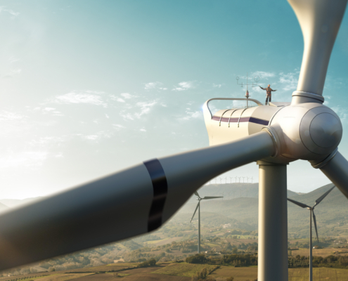 Happy engineer feel success after good work. He standing a top of windmill and looking beautiful sunset landscape