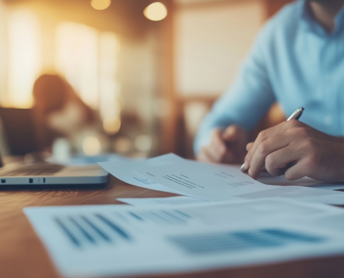A job candidate is focused on taking notes and reviewing essential documents while sitting at a spacious desk in a contemporary office setting
